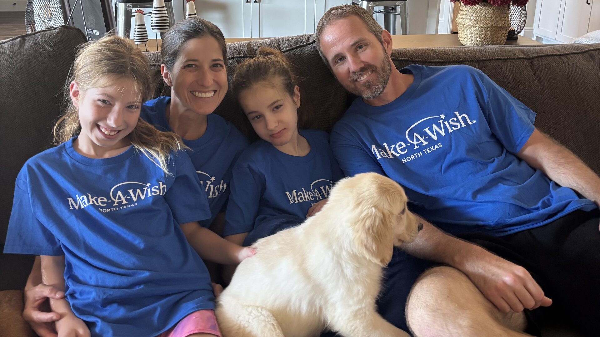 Brinlee and her family at home with their golden retriever puppy, wearing Make-A-Wish shirts